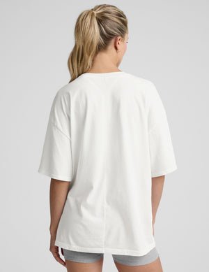 model wearing a white oversized cotton t-shirt and grey shorts against a plain background.