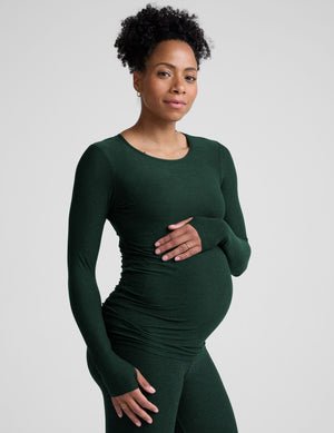 model wearing a green long-sleeve maternity top and leggings against a plain background.