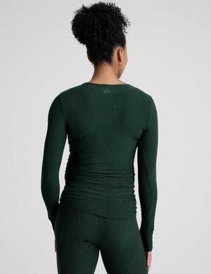 model wearing a green long-sleeve maternity top and leggings against a plain background.