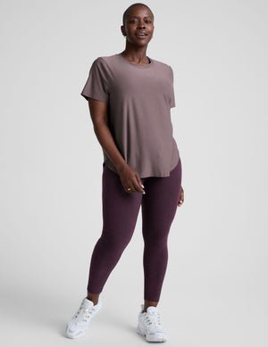 model wearing a mauve t-shirt and leggings on a plain background.