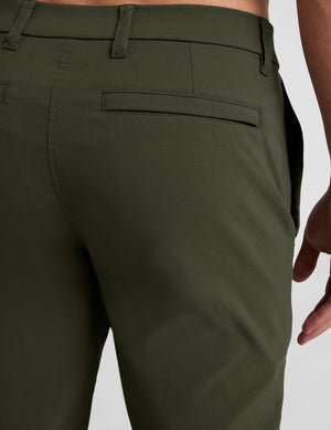 model wearing green men's chino pants on a plain background.