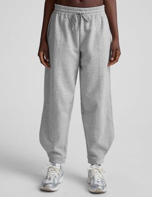 model is wearing gray fleece barrel style sweatpants against a plain background.