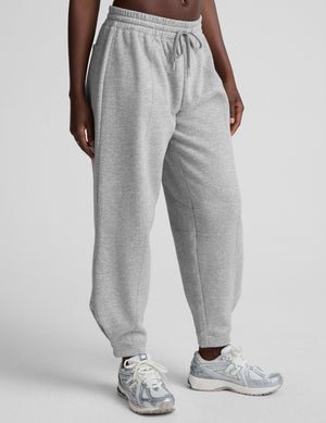 model is wearing gray fleece barrel style sweatpants against a plain background.