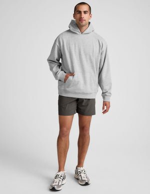 man wearing a gray hoodie and graphite shorts on a white background.