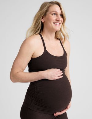 model wearing a brown maternity racerback tank top against a plain background.